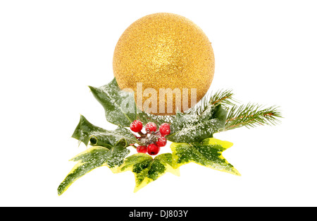 Christmas decoration of seasonal foliage and a gold bauble isolated against white Stock Photo