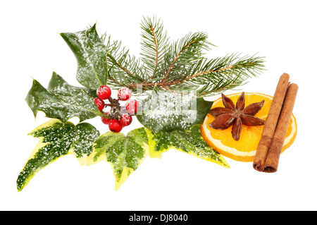 Christmas decoration of seasonal foliage, orange, cinnamon and star anise isolated against white Stock Photo