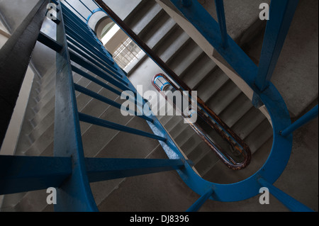 Vertigo anxiety and fear of heights a 6 floor stairwell trapped with steel blue handrail and dark and dingy flight of stairs Stock Photo