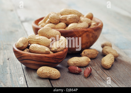 Unpeeled peanuts in bowl on wooden background closeup Stock Photo