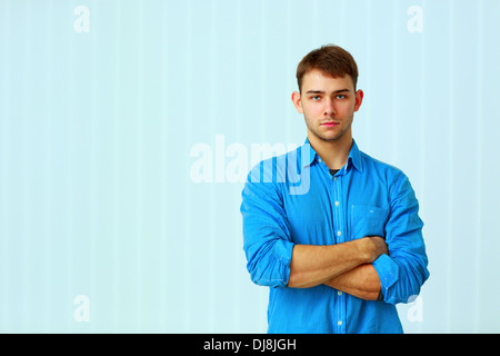 Young pensive businessman standing with arms folded at office Stock Photo