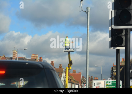 Man repairing street light up a crane. Stock Photo