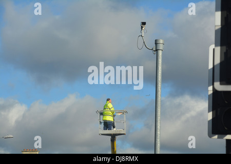 Man repairing street light up a crane. Stock Photo