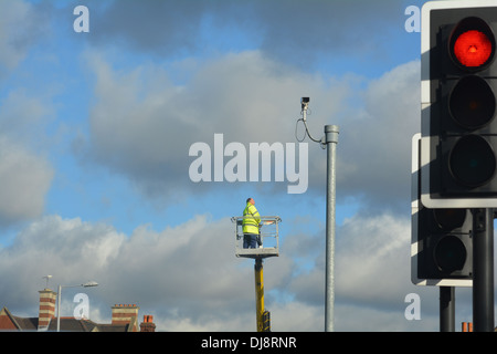 Man repairing street light up a crane. Stock Photo