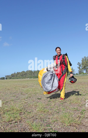 This skydiver girl landed with her parachute and is now very happy to be save back on the ground. Stock Photo