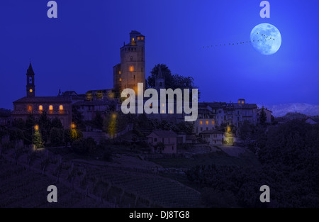 Small town on the hill under the sky with full moon at night in Piedmont, Northern Italy. Stock Photo