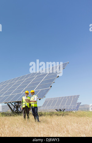 Workers standing by solar panels in rural landscape Stock Photo