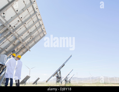 Scientists examining solar panel in rural landscape Stock Photo