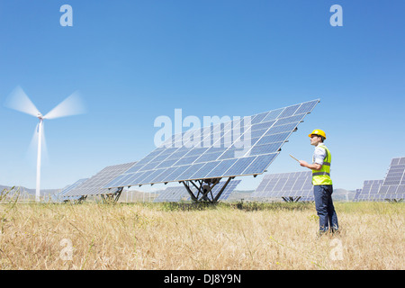 Worker examining solar panels in rural landscape Stock Photo
