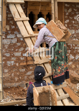 Bhutan, Wangdue Phodrang, house construction, woman labourer climbing ladder with load Stock Photo