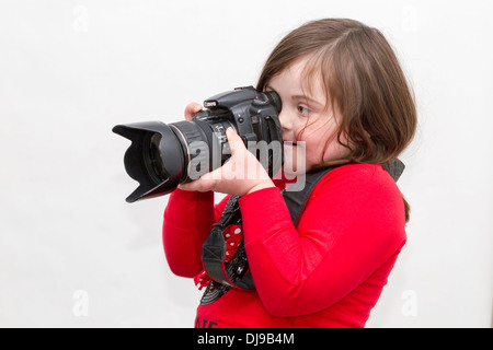 Young girl with Downs Syndrome posing with a Canon 20D Camera against a white background. Stock Photo