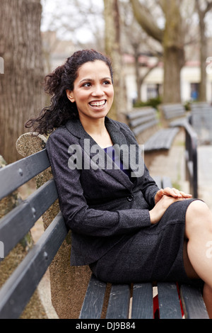 Mixed race woman sitting on park bench Stock Photo