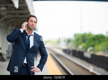 Caucasian businessman talking on cell phone on train platform Stock Photo