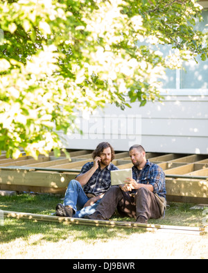Worker Showing Digital Tablet To Coworker On Call At Site Stock Photo