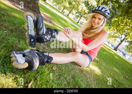Casual cheerful blonde wearing roller blades and helmet Stock Photo