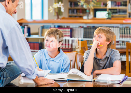 Teacher and students working in library Stock Photo