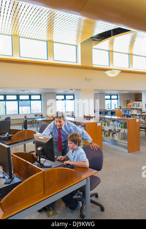 Teacher and student working at computer in library Stock Photo