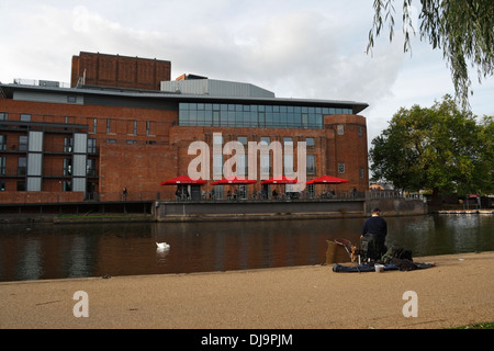 A man fishing on the banks of the river Avon in Stratford upon Avon opposite the RSC  Royal Shakespeare Company Theatre Stock Photo