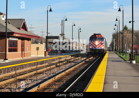 Train arriving at suburban commuter train station. Stock Photo