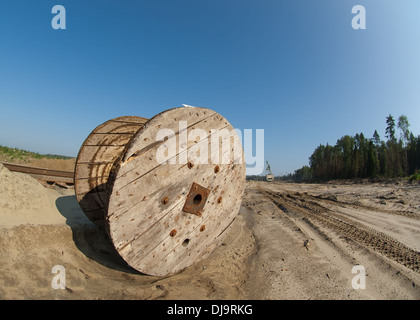 Electric wooden drum lying on a sand near the mine factory Stock Photo