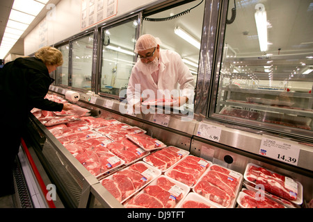 Hispanic employee wearing food safety hair net stocks with fresh meat department at a newly open COSTCO warehouse retail store Stock Photo