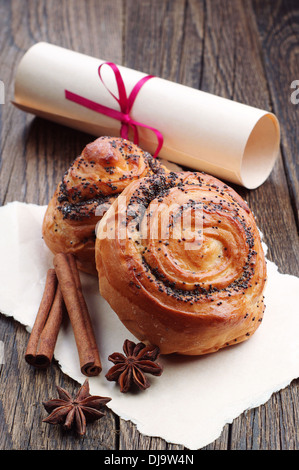 Buns with poppy seeds and roll paper tied with a red ribbon on wooden table Stock Photo