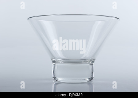 an empty glass ice cream bowl on a light gray reflecting surface Stock Photo