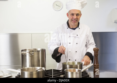 Smiling head chef holding ladle looking at camera Stock Photo
