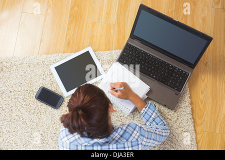 Brunette young student using her tablet and notebook for doing homework Stock Photo