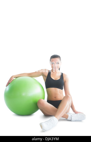 Front view of attractive brunette woman posing sitting next to an exercise ball Stock Photo