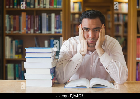 Handsome man sitting in front of an opened book in library Stock Photo