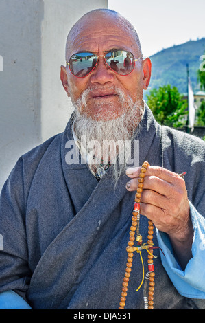 Old bald Bhutanese Budhhist man praying Stock Photo