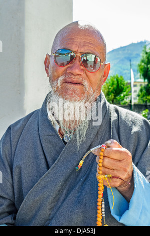 Old bald Bhutanese Budhhist man praying Stock Photo