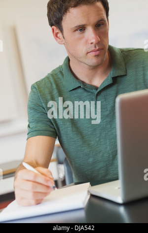 Focused handsome mature student using his notebook for learning Stock Photo