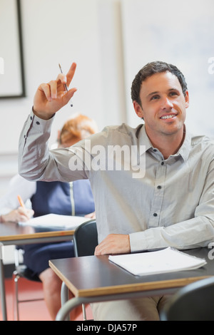Smiling handsome mature student raising his hand Stock Photo