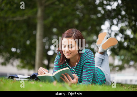 Calm casual student lying on grass reading Stock Photo