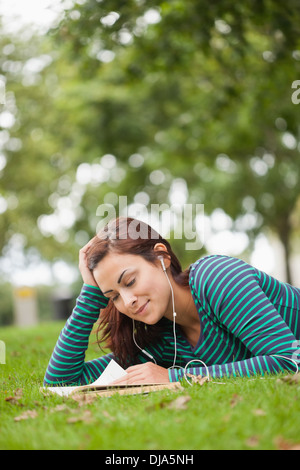 Casual student lying on grass reading Stock Photo