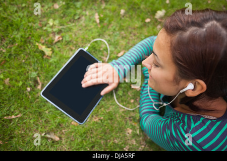 Casual student lying on grass using tablet Stock Photo