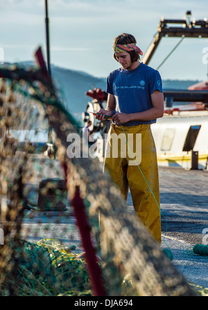 Young fisherman mending fishing nets, Palamos, Spain Stock Photo