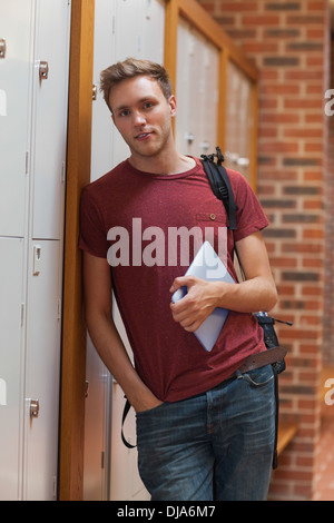 Handsome student leaning against lockers holding tablet Stock Photo