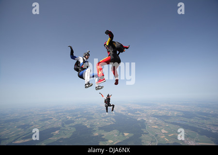 Freefly skydiving team is training formation back/sit-flying over a spectacular land and fields scenery in the sky with 130 MPH. Stock Photo