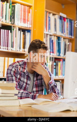 Handsome thoughtful student using computer Stock Photo