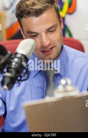 Well dressed smiling radio host moderating holding clipboard Stock Photo