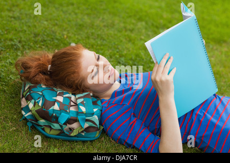 Gorgeous focused student lying on grass reading notes Stock Photo