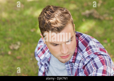 Handsome serious student sitting on grass Stock Photo