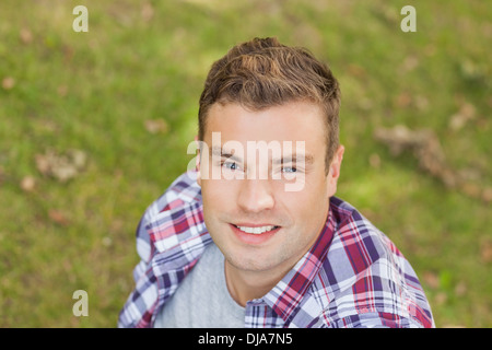 Handsome smiling student sitting on grass Stock Photo