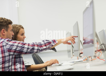Two students working on computer pointing at it Stock Photo