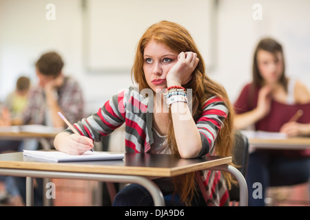 Bored female student with others writing notes in classroom Stock Photo