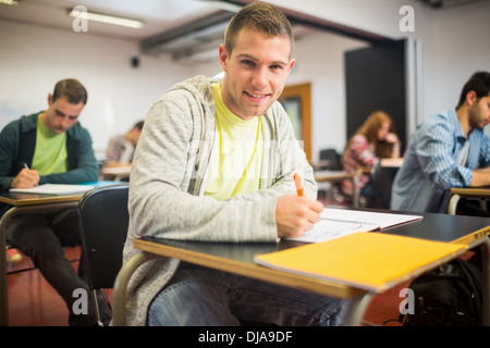 Smiling student with others writing notes in classroom Stock Photo
