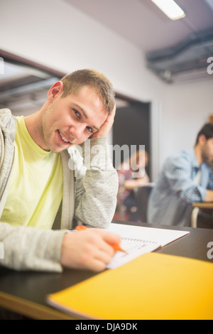 Male student with others writing notes in classroom Stock Photo